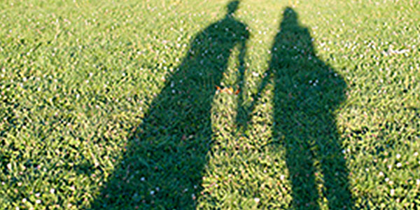 Image of a reflection on grass of two people holding hands